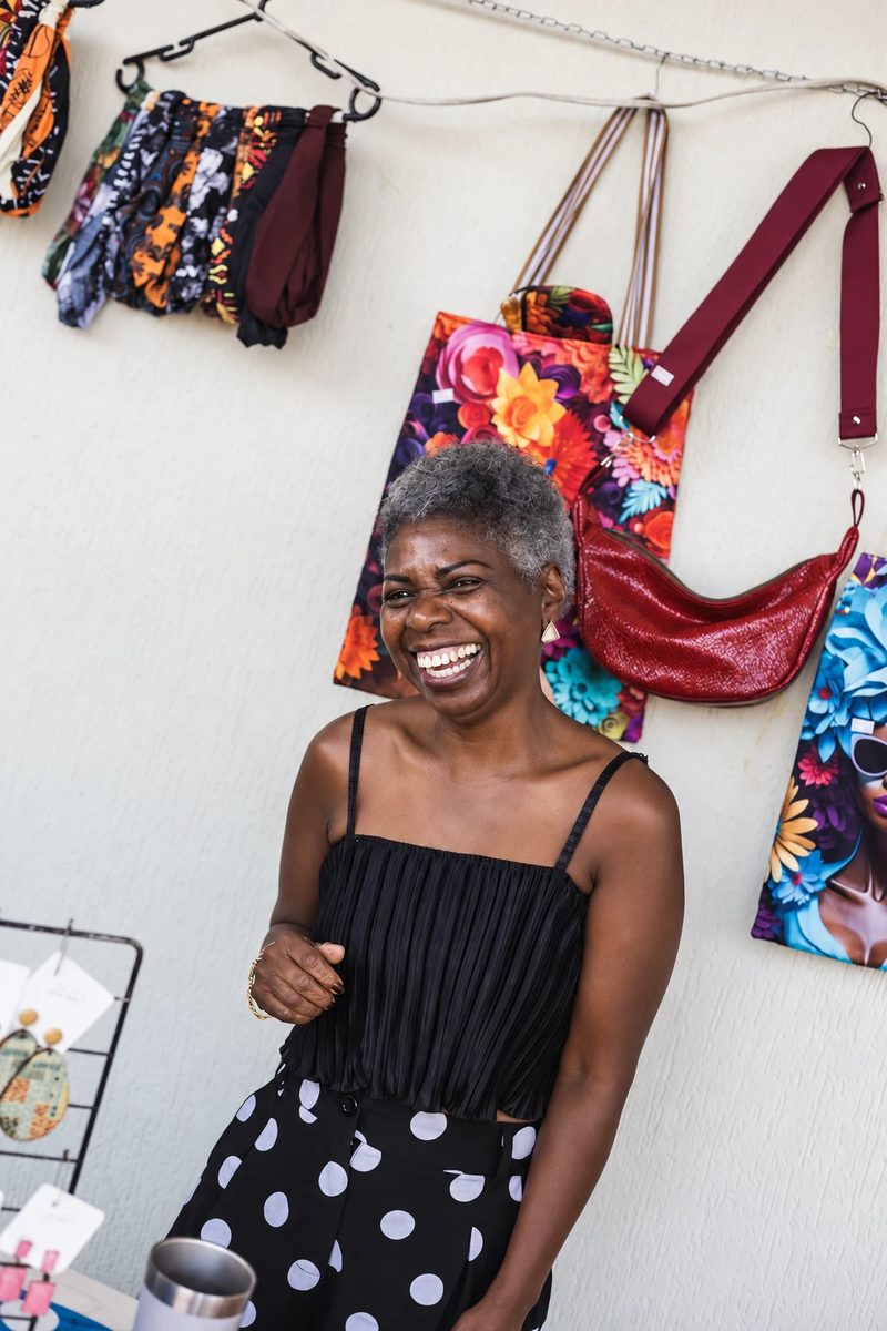 A smiling woman in front of the handbags in her shop