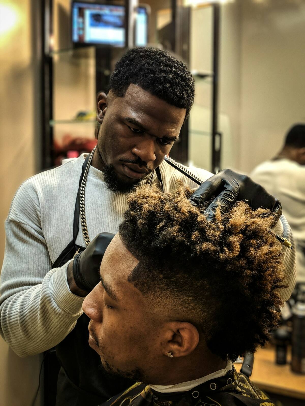 A barber shaping a customer’s fade